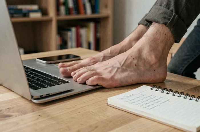 Pés de uma pessoa trabalhando de casa com laptop, evocando a venda online e o trabalho independente